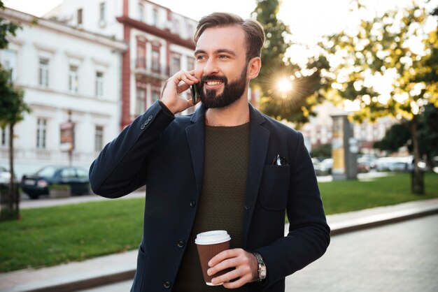 Retrato de un apuesto hombre sonriente hablando por teléfono móvil