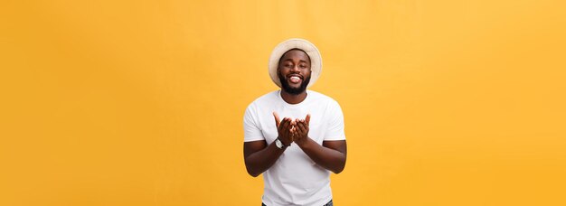 Retrato de un apuesto joven africano sonriendo con una camiseta blanca de fondo amarillo