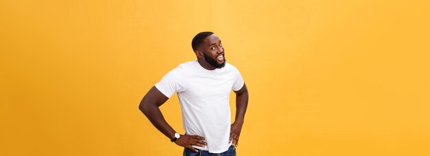 Retrato de un apuesto joven africano sonriendo con una camiseta blanca de fondo amarillo