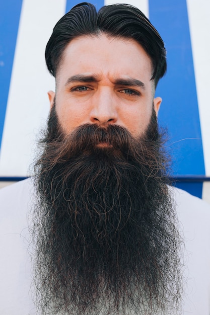 Foto gratuita retrato de un apuesto joven con barba larga mirando a cámara