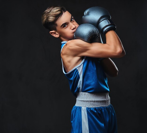 Retrato de un apuesto joven boxeador durante los ejercicios de boxeo, centrado en el proceso con un facial serio y concentrado.