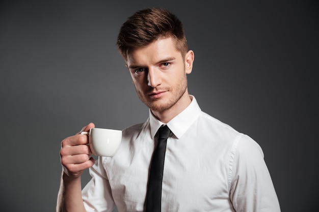 Retrato de un apuesto joven empresario con taza de café