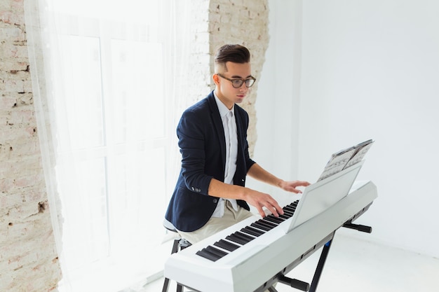 Retrato de un apuesto joven mirando la hoja musical tocando el piano