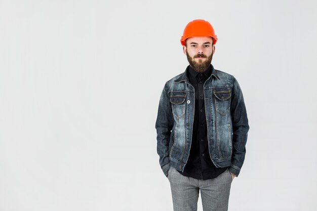 Retrato de un arquitecto masculino que usa el casco de protección contra el telón de fondo blanco