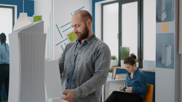 Retrato de un arquitecto que sostiene un modelo de construcción para crear un proyecto arquitectónico y una estructura. Constructor de hombres mirando el diseño de la maqueta para diseñar el plan de construcción y la arquitectura urbana.