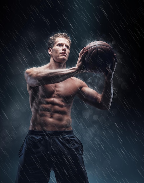 Retrato artístico de un jugador de bascetball mojado sin camisa bajo gotitas.