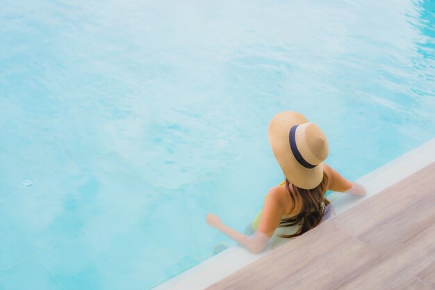 Retrato asiática hermosa joven feliz sonrisa relajarse en la piscina al aire libre en vacaciones