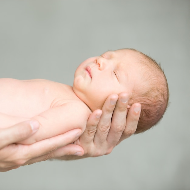 Retrato de un asimiento de recién nacido durmiente en las manos