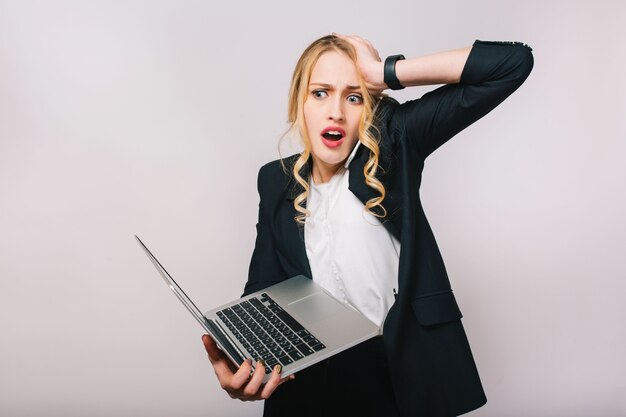 Retrato asombrado mujer rubia joven ocupada que trabaja con la computadora portátil. Hablar por teléfono, error, estado de ánimo alterado, llegar tarde, oficinista, emociones verdaderas