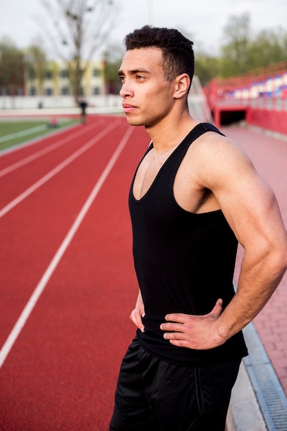 Retrato de un atleta masculino confiado de pie en la pista de atletismo