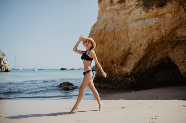 Retrato de una atractiva chica rubia con el pelo largo posando en la playa desierta.