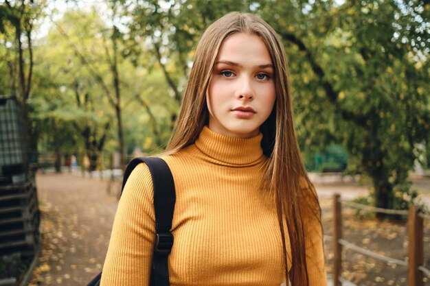 Retrato de una atractiva estudiante mirando con confianza a la cámara en el parque de la ciudad