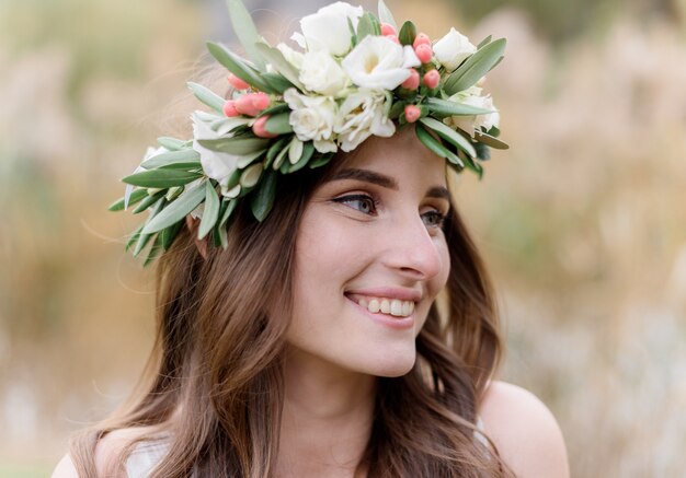 Retrato de una atractiva mujer morena en una corona hecha de eustomas con una hermosa sonrisa