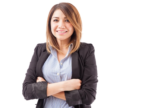 Retrato de una atractiva mujer de negocios hispana con los brazos cruzados sobre un fondo blanco con mucho espacio para copiar