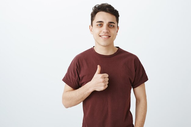 Retrato de atractivo empresario masculino seguro en traje casual con pulgar hacia arriba