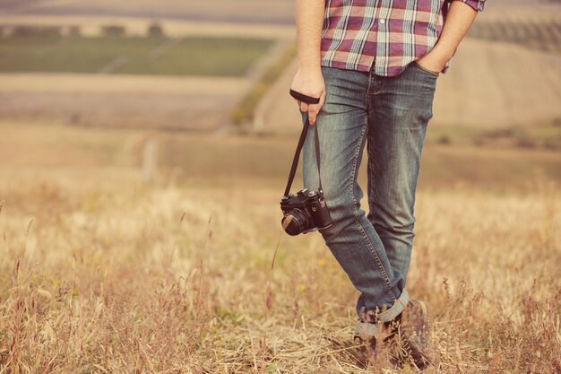 Retrato de atractivo fotógrafo masculino al aire libre al atardecer. Joven con una cámara en mano