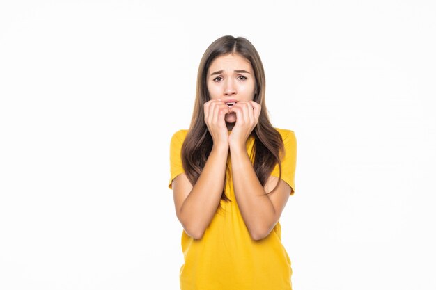 Retrato de atractivo sorprendido emocionado asustado gritando adolescente, cogidos de la mano en la cabeza, boca abierta con cabello largo castaño, aislado sobre la pared blanca