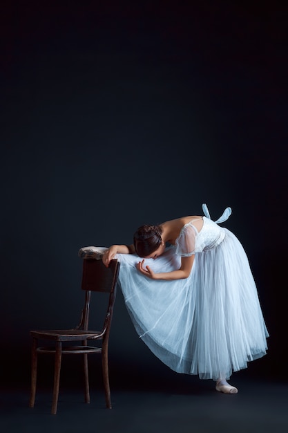 Retrato de la bailarina clásica en vestido blanco en sala negra