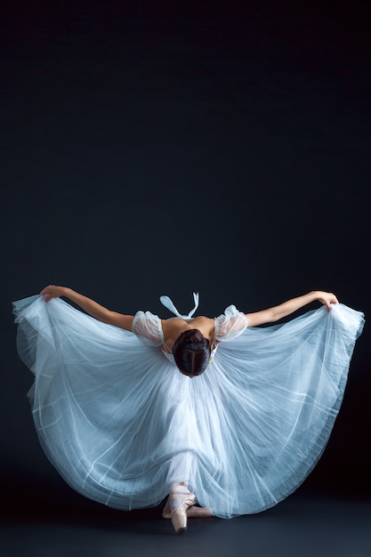 Retrato de la bailarina clásica en vestido blanco sobre pared negra