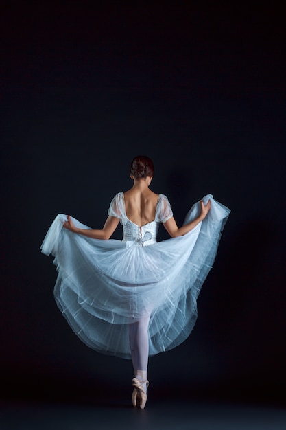 Retrato de la bailarina clásica en vestido blanco sobre pared negra