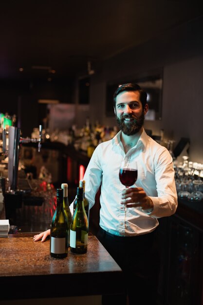 Foto gratuita retrato de barman con copa de vino tinto