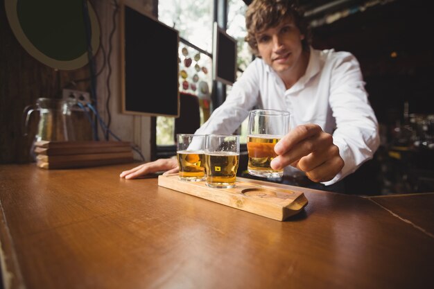 Retrato de barman sosteniendo whisky vaso de chupito en barra de bar