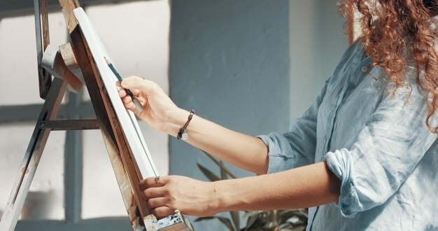 Retrato de una bella artista de pelo largo trabajando en su lienzo en un estudio