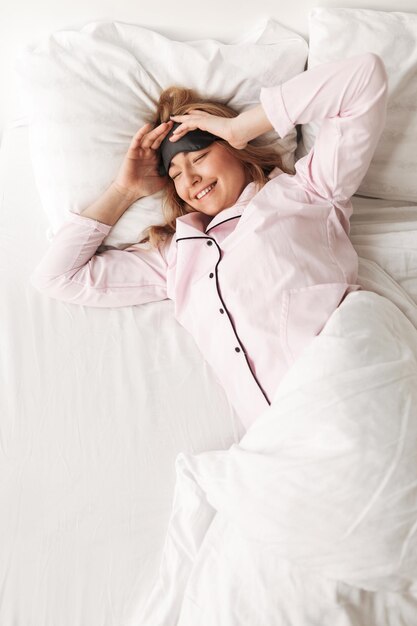 Retrato de una bella dama sonriente acostada en la cama en casa