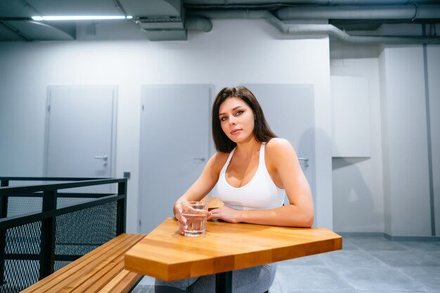 Retrato de bella dama en top deportivo con vaso de agua