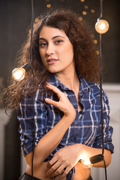 Foto gratuita retrato de una bella joven modelo en camisa a cuadros posando junto a las lámparas