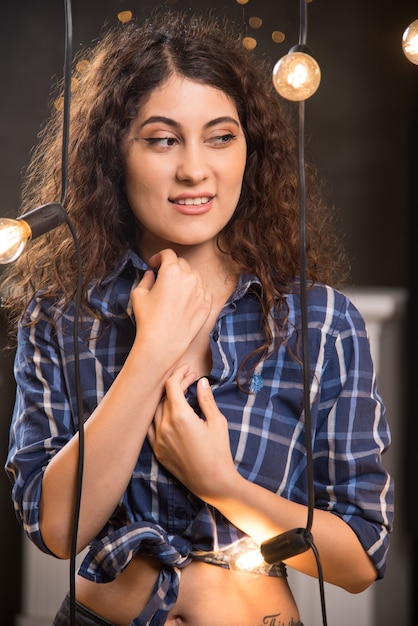 Retrato de una bella joven modelo en camisa a cuadros posando junto a las lámparas