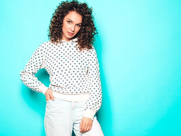 Retrato de la bella modelo sonriente con peinado afro rizos vestido con ropa hipster de verano. Mujer divertida y positiva de moda con capucha blanca