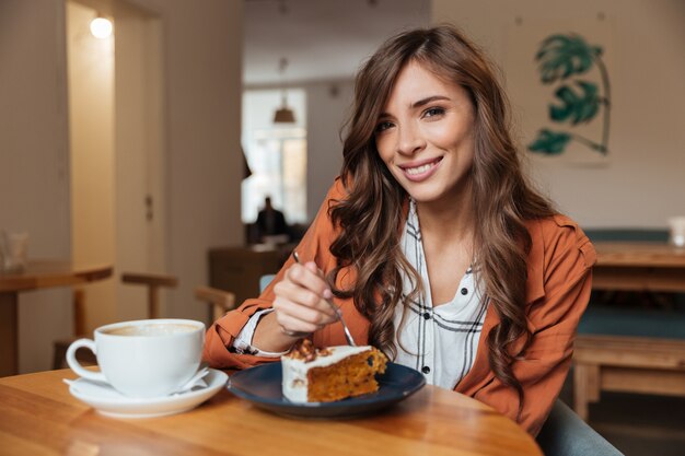 Retrato de una bella mujer comiendo un pedazo de pastel