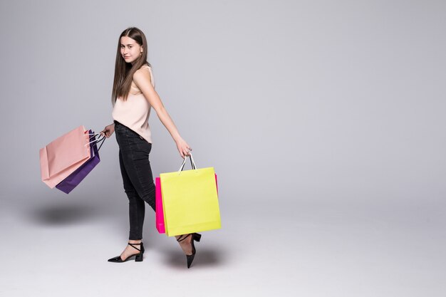 Retrato de una bella mujer joven posando con bolsas de compras aisladas en la pared blanca