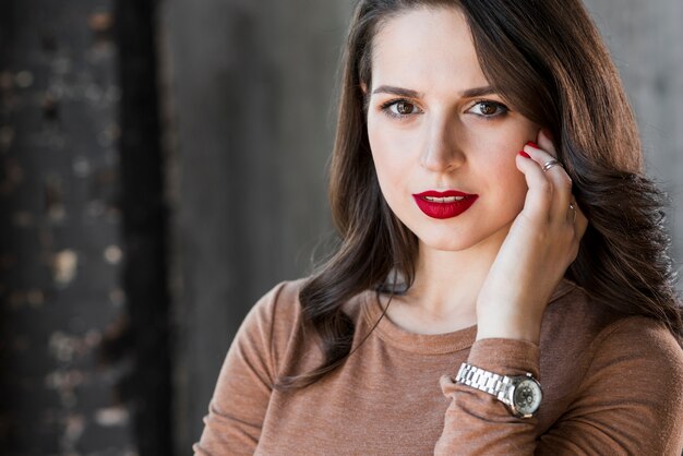 Retrato de una bella mujer joven con reloj de pulsera en su mano mirando a cámara