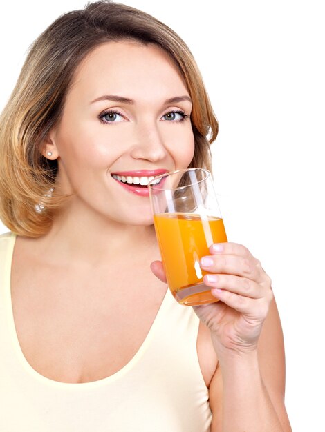 Retrato de una bella mujer joven con un vaso de jugo de naranja aislado en blanco.