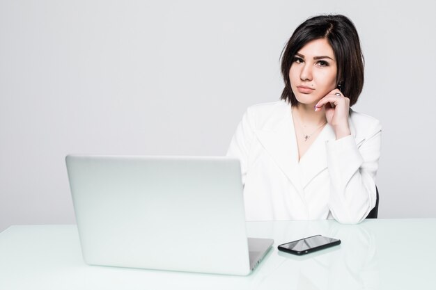 Retrato de una bella mujer de negocios sentada en el escritorio trabajando aislado en blanco