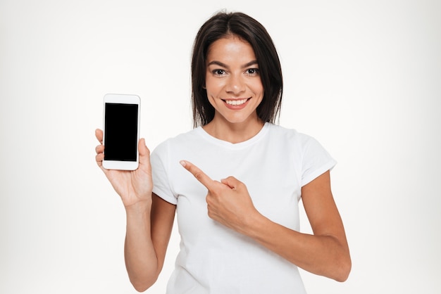 Retrato de una bella mujer que presenta el teléfono móvil de pantalla en blanco