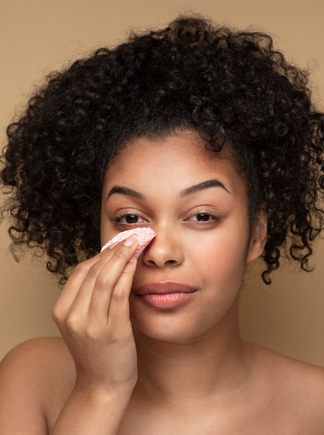 Retrato de una bella mujer quitando su maquillaje con una almohadilla