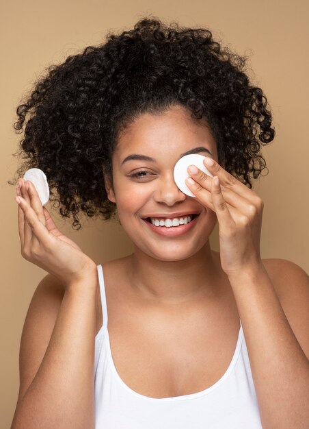 Retrato de una bella mujer quitando su maquillaje con almohadillas