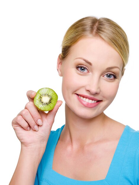 Retrato de una bella mujer rubia sonriente con kiwi cerca de ella bastante