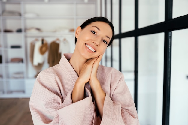 Retrato de una bella mujer sana en bata de baño posando a la cámara en el interior