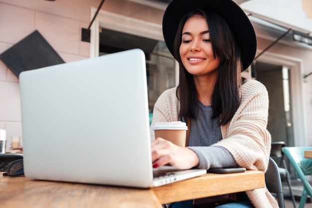 Retrato de una bella mujer sonriente escribiendo en la computadora portátil