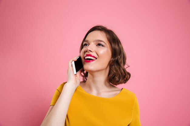 Retrato de una bella mujer sonriente hablando por teléfono móvil