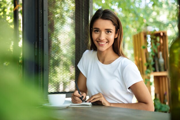 Retrato de una bella mujer sonriente haciendo notas