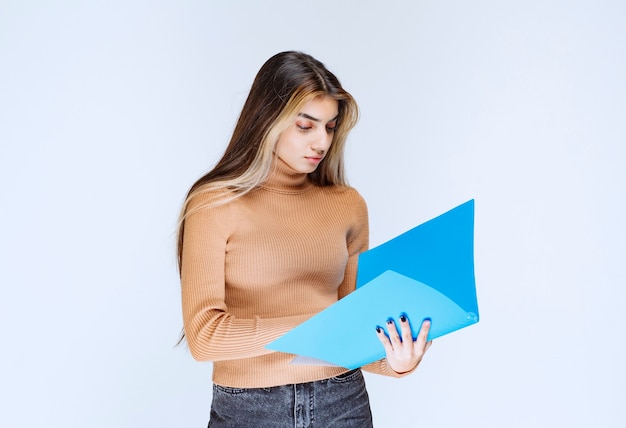 Foto gratuita retrato de una bella mujer sosteniendo una carpeta contra la pared blanca.