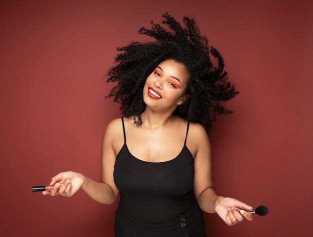 Foto gratuita retrato de una bella mujer sosteniendo lápiz labial y pincel de maquillaje