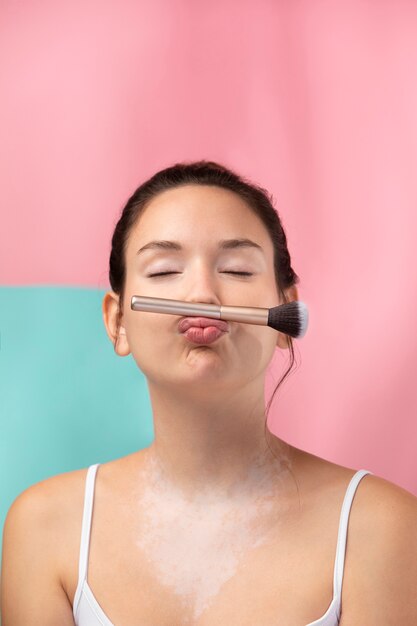 Retrato de una bella mujer sosteniendo un pincel de maquillaje con sus labios