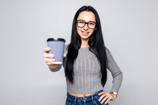 Retrato de una bella mujer sosteniendo una taza de café para llevar aislada sobre la pared gris