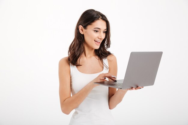 Retrato de una bella mujer vestida con una camiseta sin mangas usando laptop